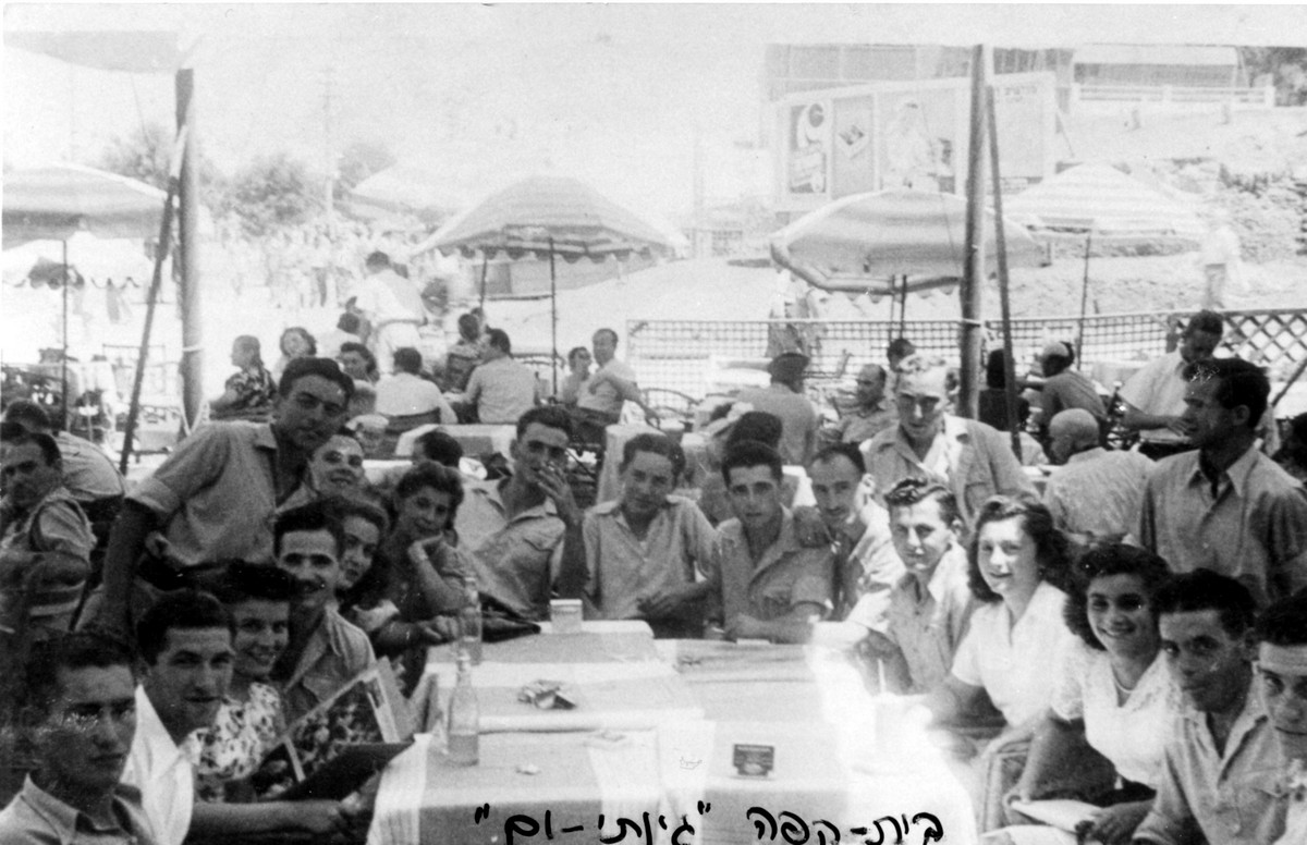 פלוגה ד התל-אביבית 1947-1941 תיאור התמונה: בית קפה- "גינתי-ים" , מופיעים בתמונה: בני קפלן, (?), (?), אהרון ידידיה, שמואל רוזנפלד, משה גולדפרב, ברוך יקותיאלי, עומד: יעקב נויברג, נתקבל מ: שמואל רוזנפלד: ניצה (צרפת) תמונה